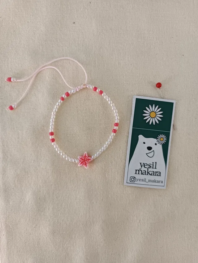 Ortasında pembe bir deniz yıldızı olan inci boncuklu bileklik